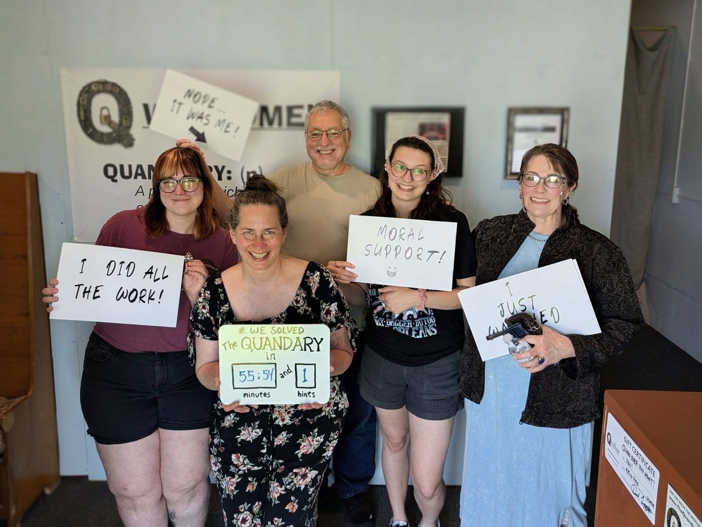 Five players holding signs reading I did all the work, moral support and I just watched, with a board showing 55:54 and 1 hint.